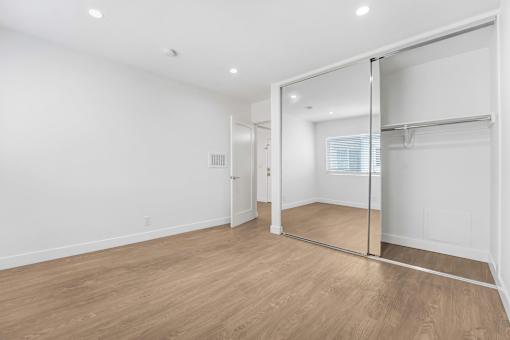 A room with a sliding glass door and wooden flooring.