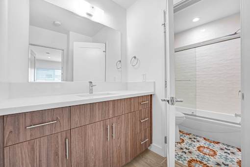 A bathroom with a sink, mirror, and wooden cabinets.
