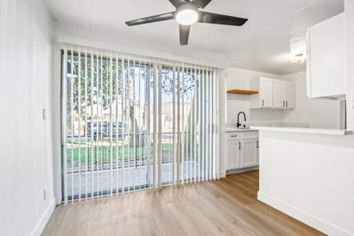 A white kitchen with a sliding glass door leading to a backyard.