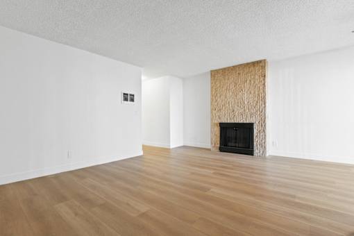 A room with a fireplace and wood flooring.