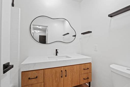 A white sink with a black faucet and a mirror above it.