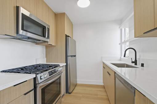 A kitchen with a stove, microwave, dishwasher, and sink.