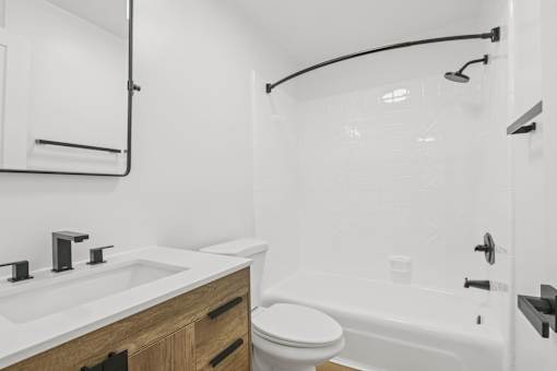 A white bathroom with a toilet, sink, and bathtub.