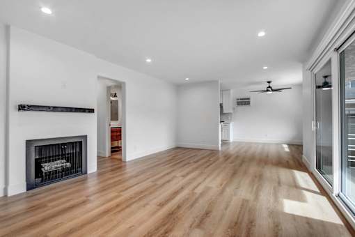 A spacious room with a fireplace and wooden flooring.