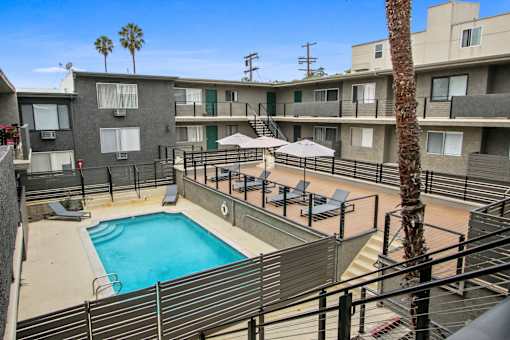 A pool surrounded by apartment buildings and palm trees.