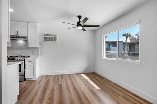 A room with a ceiling fan and a window overlooking a building.