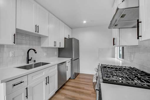 A modern kitchen with white cabinets and a black stove top.