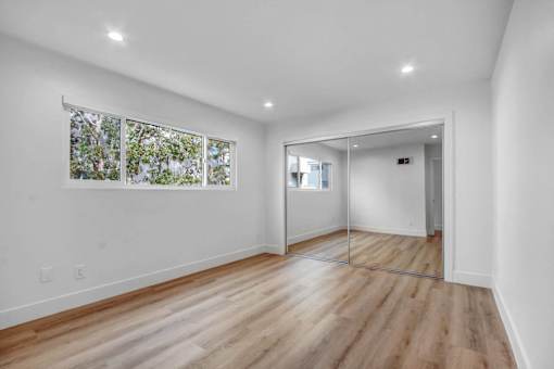 A room with a wooden floor and a large mirror on the wall.