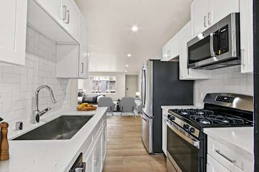 A modern kitchen with white cabinets and black appliances.