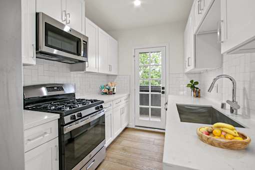 A kitchen with white cabinets and a stainless steel stove top.