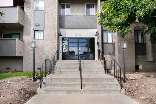 A concrete building with a black railing and steps leading to the entrance.