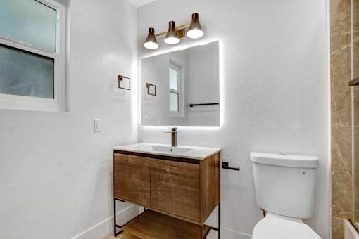 A bathroom with a white toilet and a wooden vanity.