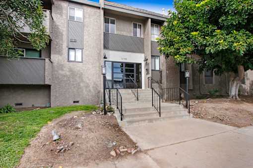 A concrete building with a black railing and steps leading up to the entrance.
