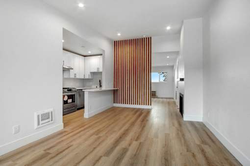 A modern kitchen with wooden floors and white walls.