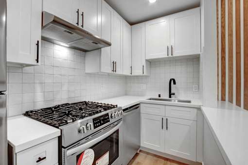 A modern kitchen with white cabinets and a stainless steel range hood.