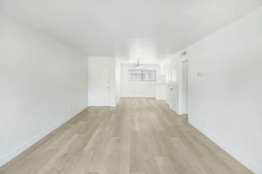 A long, empty hallway with wooden floors and white walls.