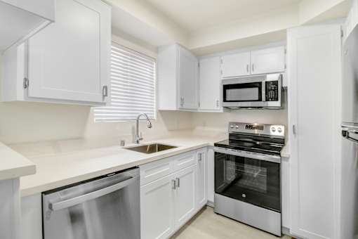 A white kitchen with a stainless steel dishwasher and oven.