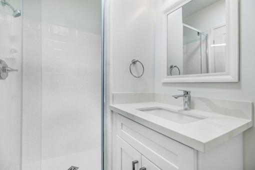A white bathroom with a sink and mirror.