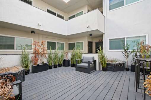 A balcony with a grey bench and black planters.
