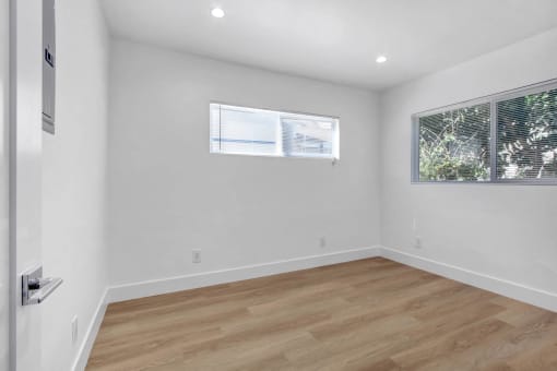 a living room with white walls and wood floors and a window