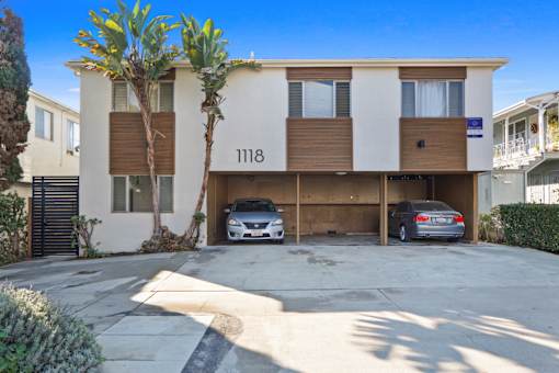 A modern two-story apartment building with a garage and a car parked in front.
