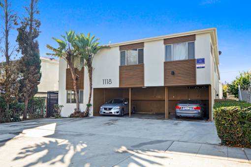 A two-story building with the number 118 on the front has a car parked in the garage.