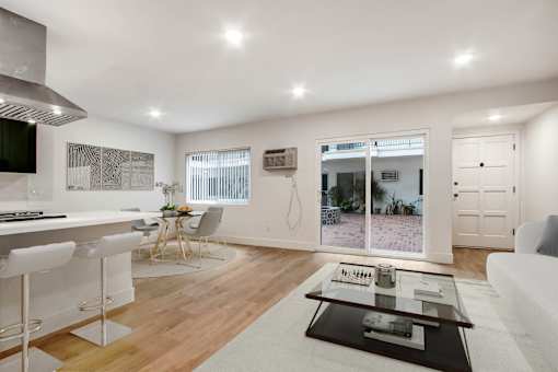 A modern kitchen with white cabinets and a dining area with a table set for four.