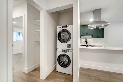 A white laundry machine is in a small, modern room.