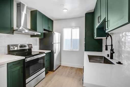 A kitchen with green cabinets and stainless steel appliances.