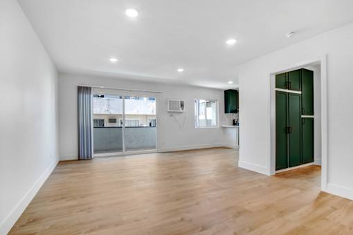 A spacious room with wooden flooring and white walls.