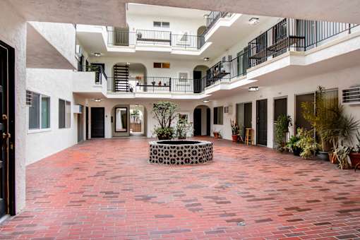 A courtyard with a red tile floor and a fountain in the middle.
