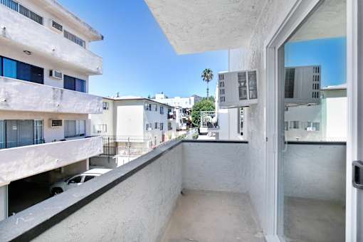 A white building with a balcony overlooking a street.
