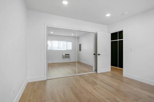 A room with a white door and a mirror on the wall.