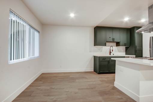 A kitchen with a white counter and wooden floors.