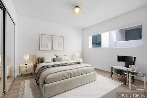 A bedroom with a large bed and a chair.