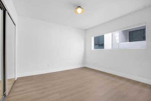 A room with a window and a wooden floor.