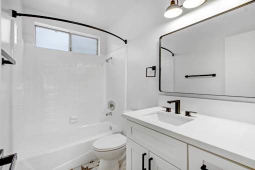 A white bathroom with a toilet, sink, and bathtub.