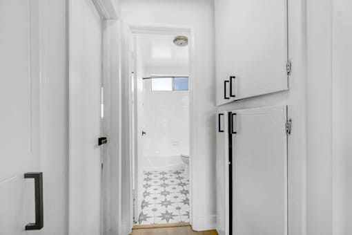 A hallway with white walls and a black door.