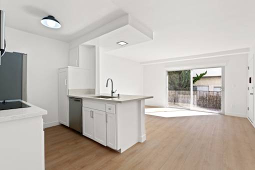 A kitchen with white cabinets and a black fridge.