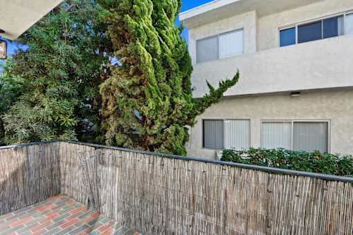 A building with a wooden fence and a tree in front of it.
