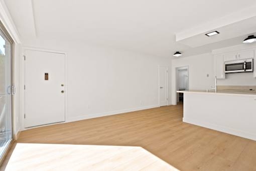 A kitchen with white cabinets and a wooden floor.