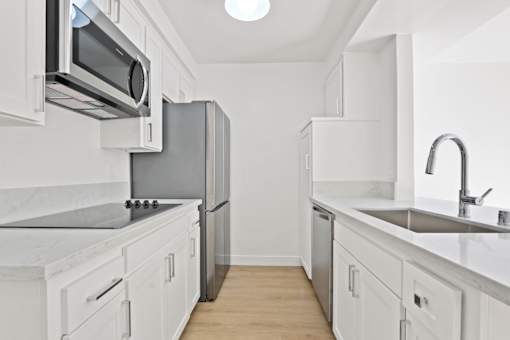 A kitchen with white cabinets and a black countertop.
