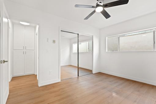 A room with a ceiling fan and a mirror on the wall.
