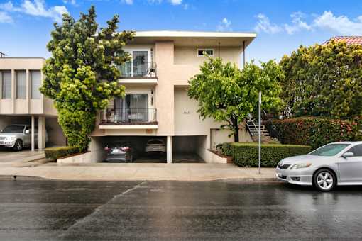 A two-story beige house with a balcony on the second floor.