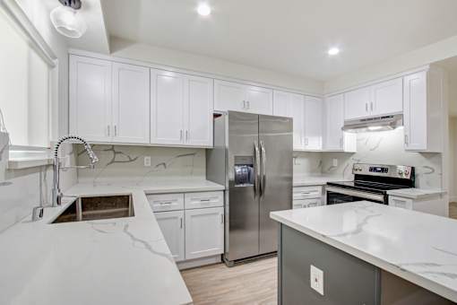 A modern kitchen with white cabinets and a marble countertop.