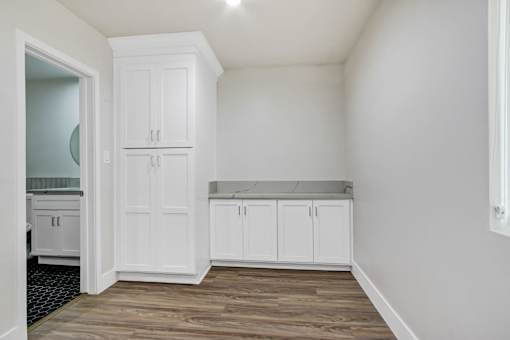 A kitchen with white cabinets and a wooden floor.