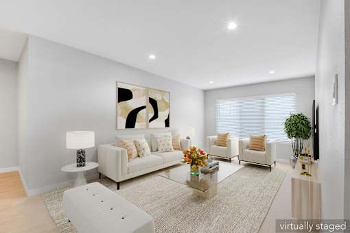 A modern living room with a white sofa, a glass coffee table, and a large abstract painting on the wall.