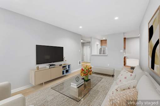 A modern living room with a flat screen TV and a glass coffee table.