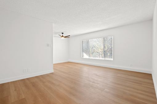 A room with a ceiling fan and a window with blinds.