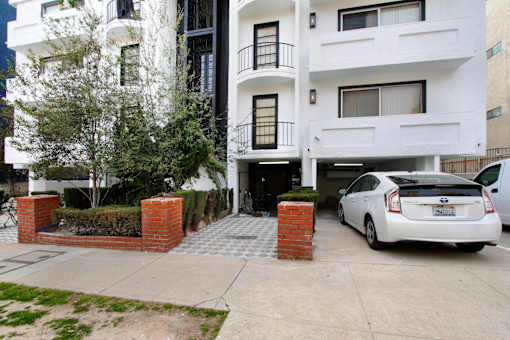 A white car is parked in front of a white building.